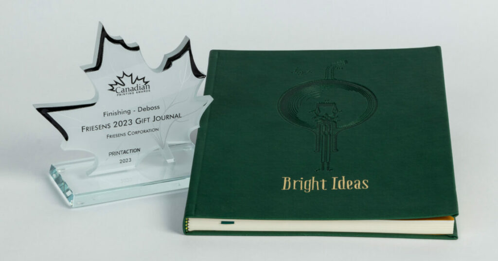 Green “Bright Ideas” journal displayed beside a maple‑leaf‑shaped Canadian Printing Awards trophy