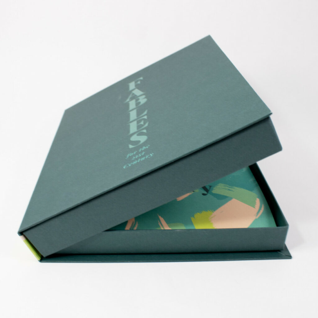 Teal three‑piece clamshell box partially open to reveal a colorful illustrated book inside.