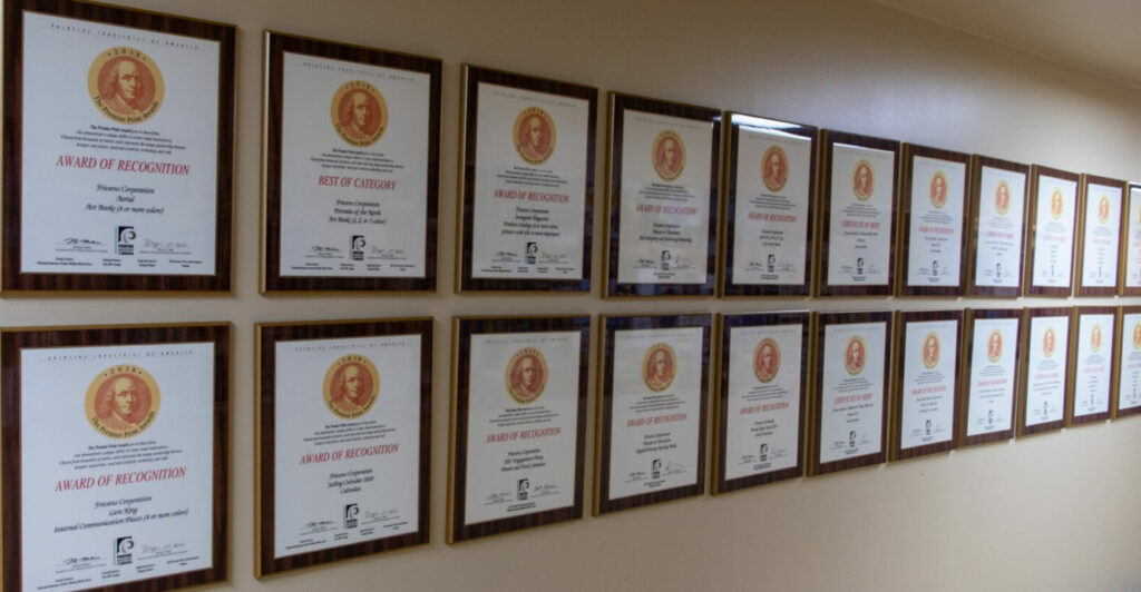 Row of framed award certificates mounted along a hallway wall.