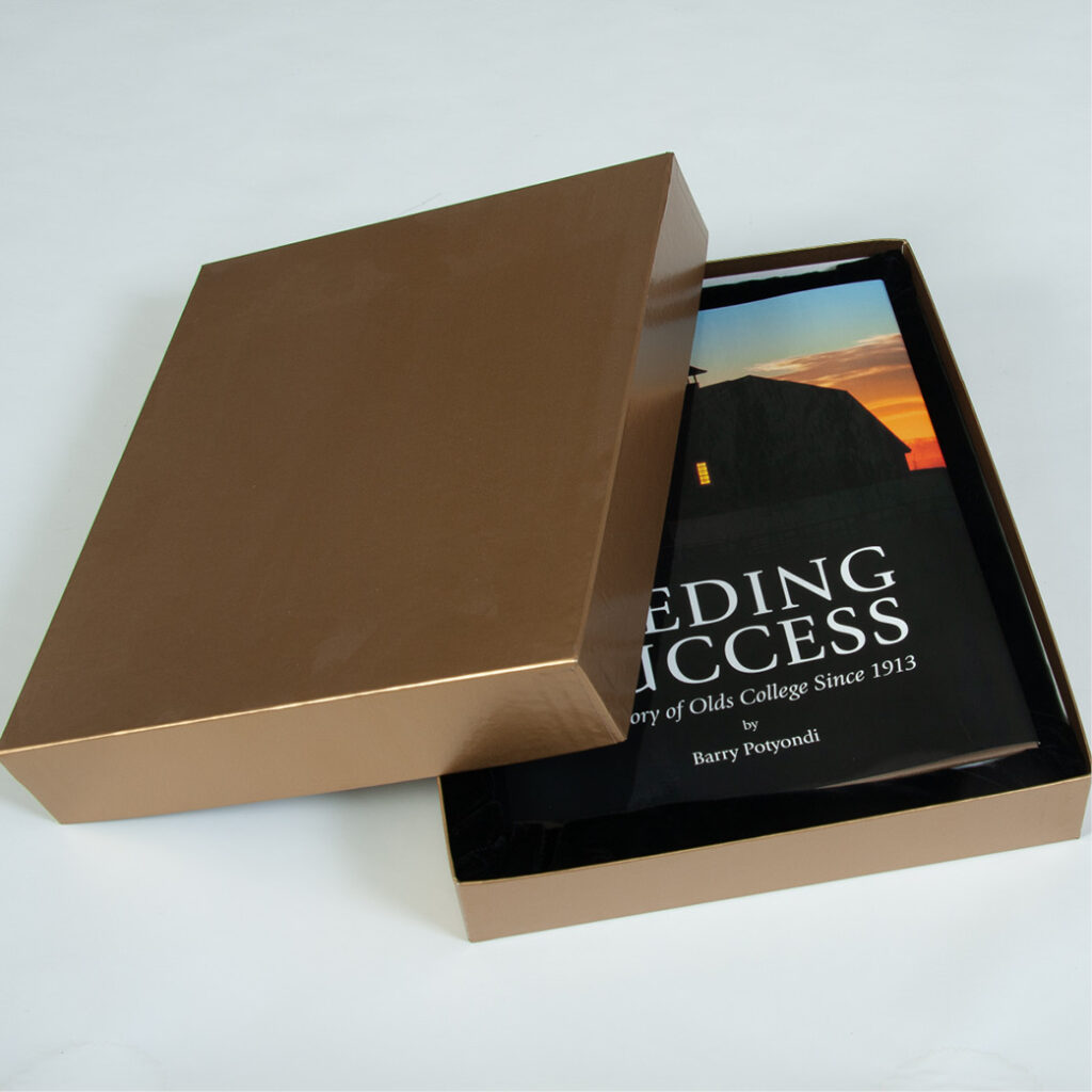 Gold telescopic box shown open with a hardcover book titled “Leading Success” inside.
