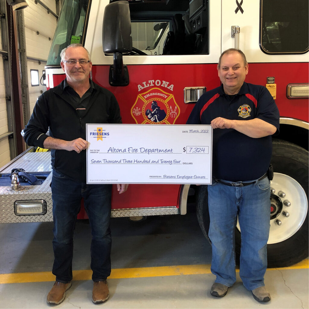 firefighters standing in front of fire truck with big cheque