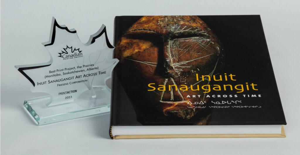 Glass award beside the book “Inuit Sanaugangit: Art Across Time” on a white background.