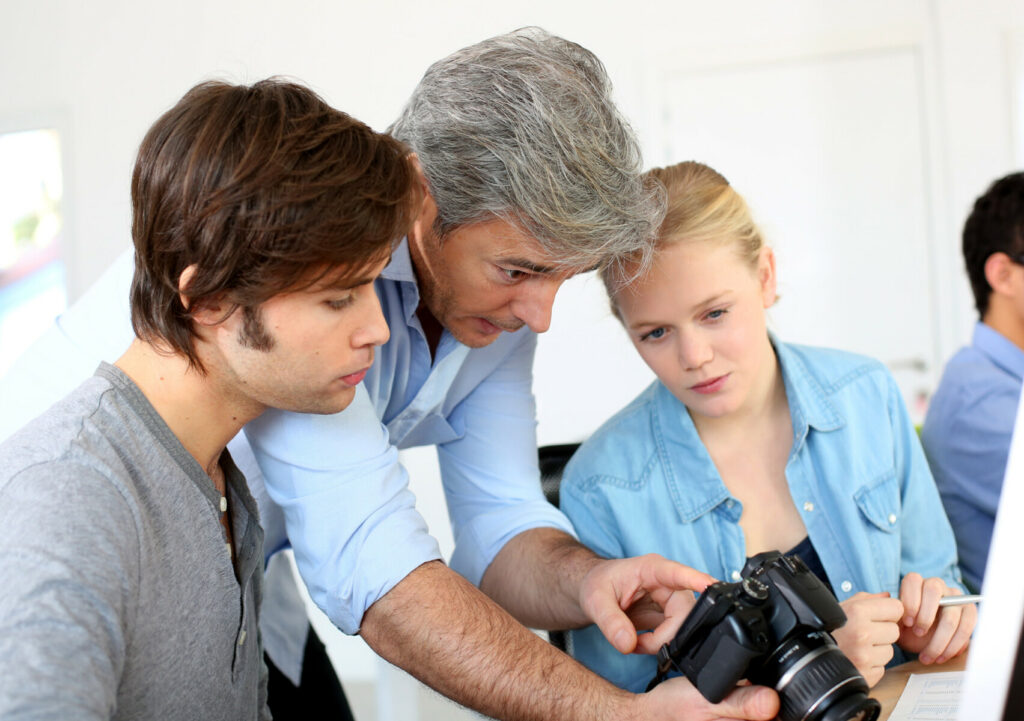 man with camera showing 2 other people 