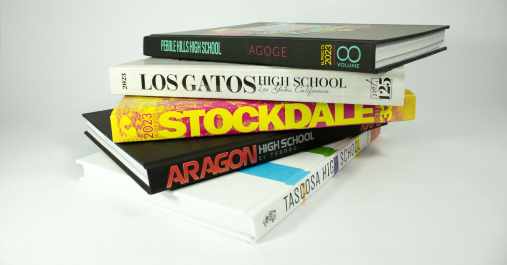Stack of colorful high school yearbooks with various spine designs and titles.