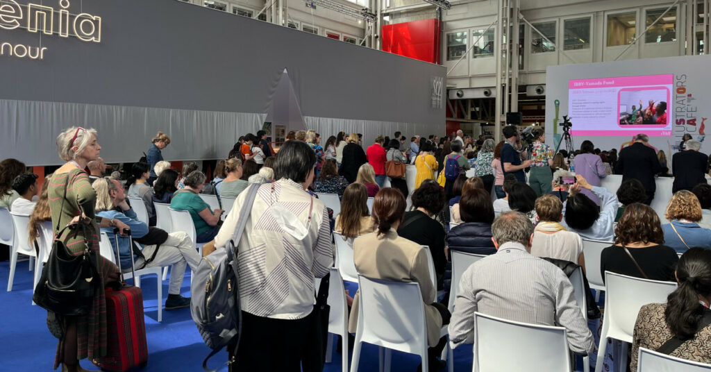Audience gathered in a presentation space at the Bologna Children’s Book Fair, watching a speaker on stage.