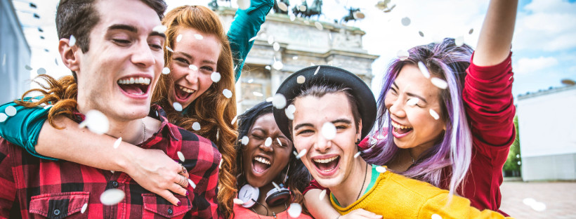 Group enjoying a festive moment outdoors with confetti falling near a historic monument.