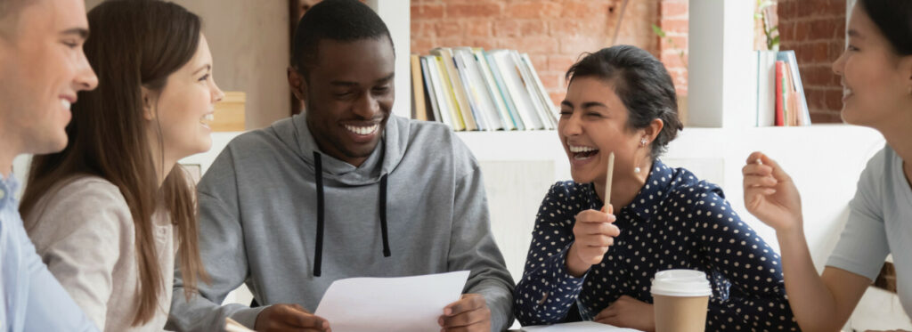 Small group gathered around a table discussing papers and notes with books and coffee nearby.