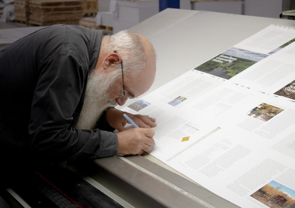 Person reviewing and signing a printed press proof on a production table
