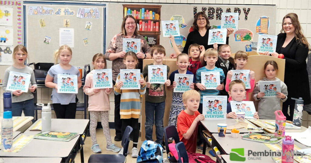 Students gathered in a classroom at Plum Coulee School holding copies of the book “We Need Everyone.”