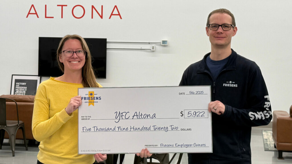 Two people holding a large donation cheque for YFC Altona inside a modern lounge area with “ALTONA” on the wall.