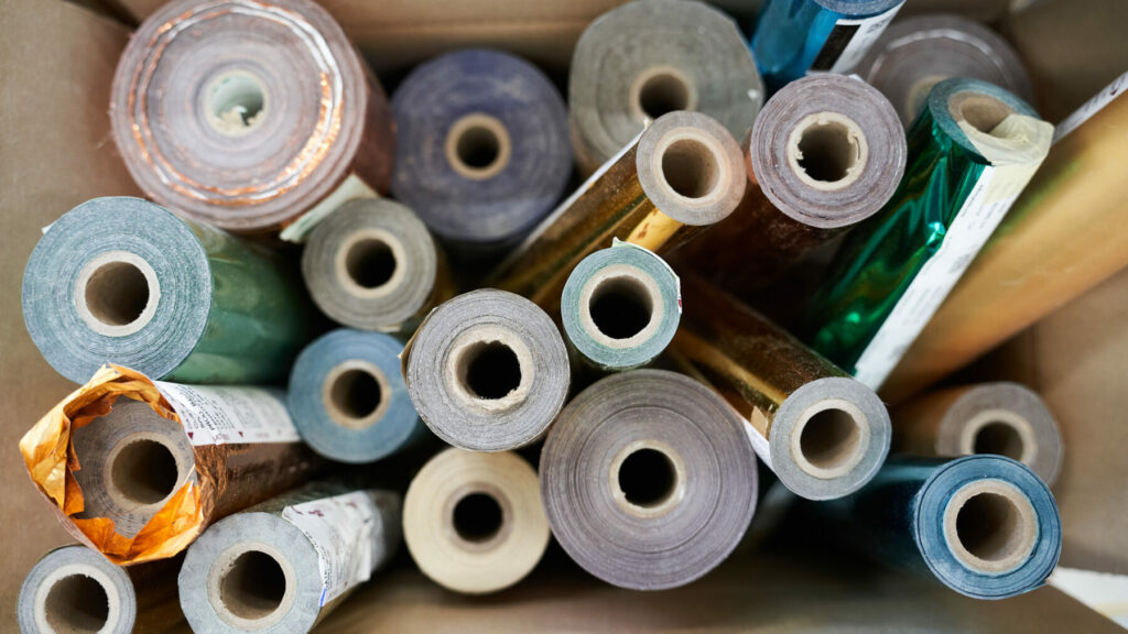 Various rolls of colored foil standing upright in a box for use in foil stamping