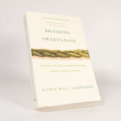 Book cover of Braiding Sweetgrass featuring a braided sweetgrass design on a light background