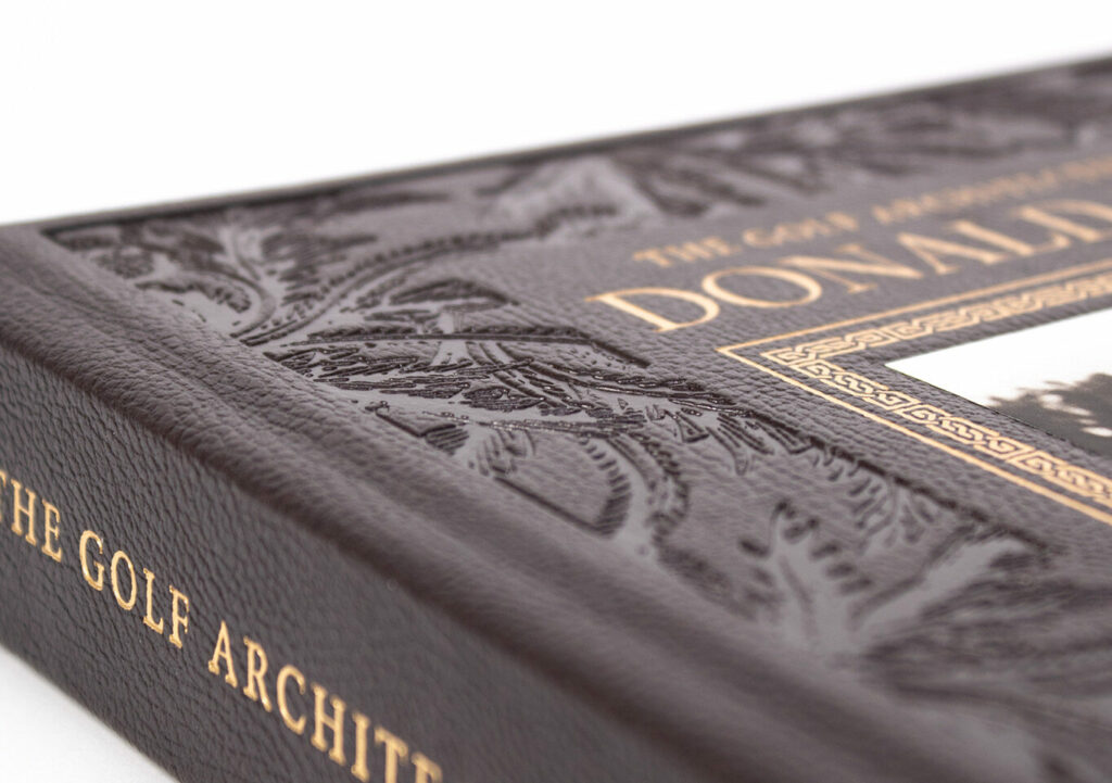 Close‑up of a debossed leather book cover with ornate patterns and gold‑stamped title text.