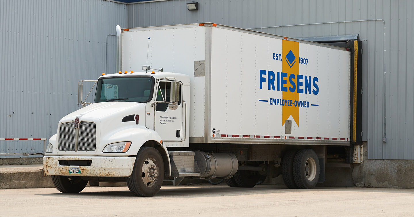 Friesens-branded delivery truck backed into a warehouse loading dock