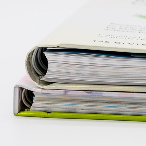 Close-up of two books showing concealed wire-o binding with coils hidden inside the hardcover spine