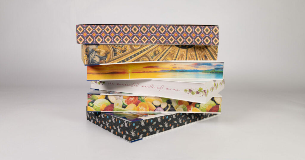 A stack of books with colorful sprayed edges featuring artistic patterns and illustrations.