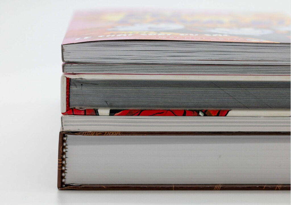 Close-up of a stacked books showing exposed page edges and different binding thicknesses on a white background.