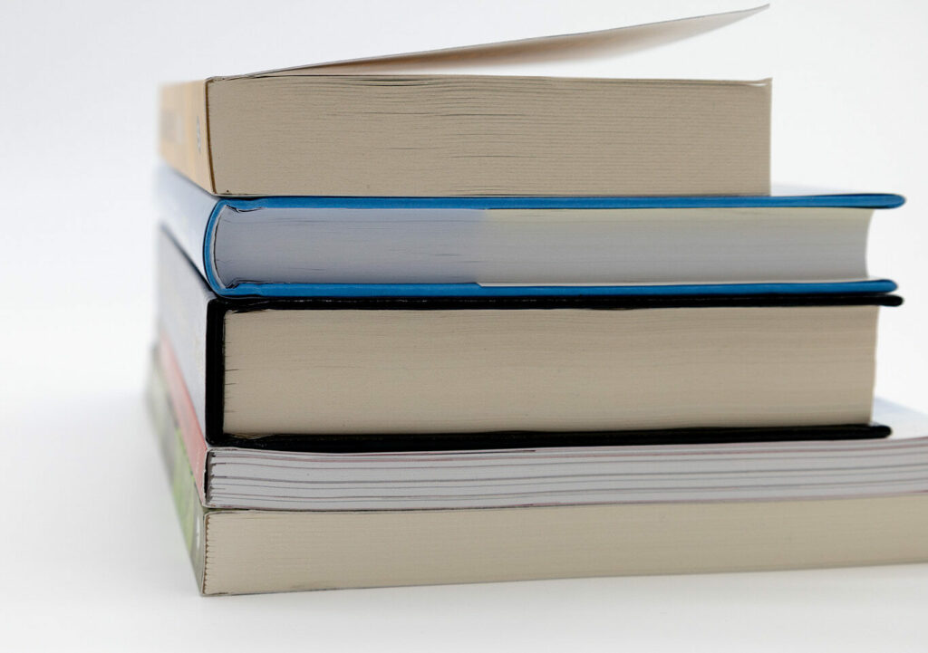 Close-up of stacked perfect bound books showing smooth glued spines on a white background.