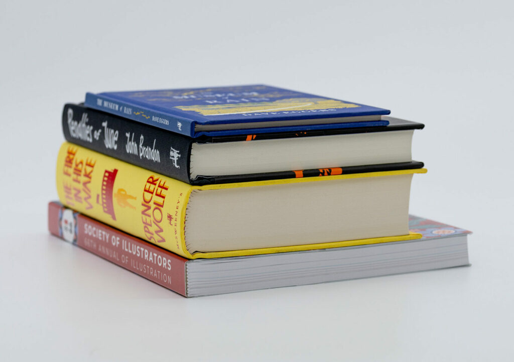 Stack of hardcover books with colorful spines on a white background.
