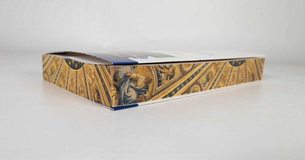 Close-up of a book featuring an ornate, gold-toned sprayed edge with detailed artwork.