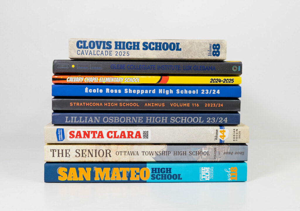 Stack of colorful high school yearbooks showing different spine designs and school names in a clean studio setting