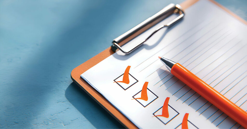 Orange pen resting on a clipboard with several checked boxes.