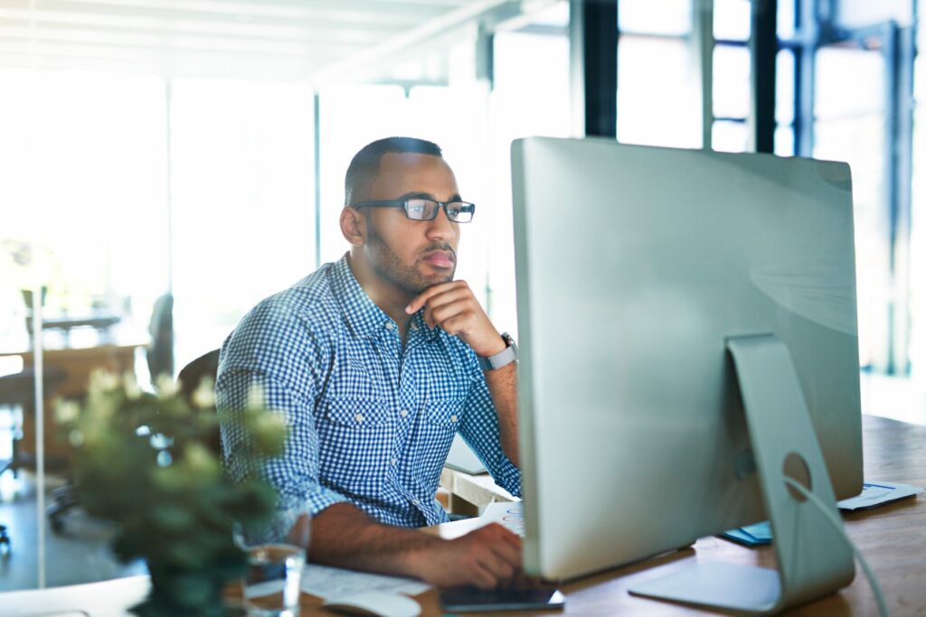 Person working at a large desktop computer in a bright, modern office environment.