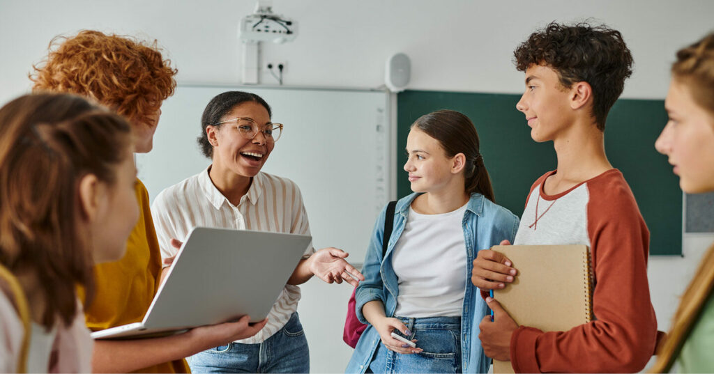 A group of students talking and sharing materials together in a classroom setting.