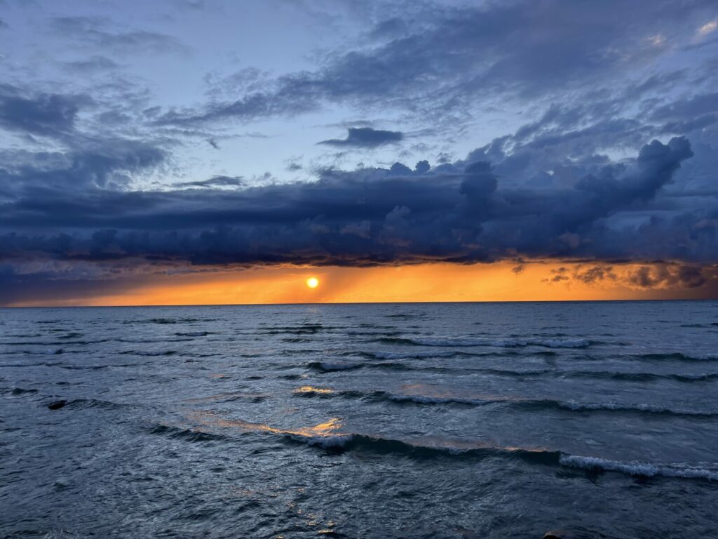 Golden sunset over Lake Huron with waves and dramatic clouds along the horizon.