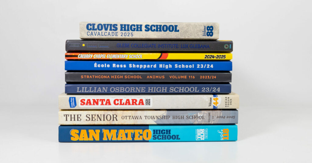 Stack of colorful hardcover yearbooks arranged in a neat pile against a plain white background.