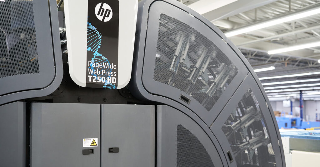 HP PageWide Web Press T250 HD inside a print facility, showing curved enclosure and internal components.