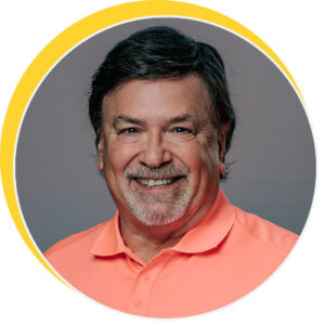 Person wearing a coral polo shirt against a grey background with a yellow circular border.