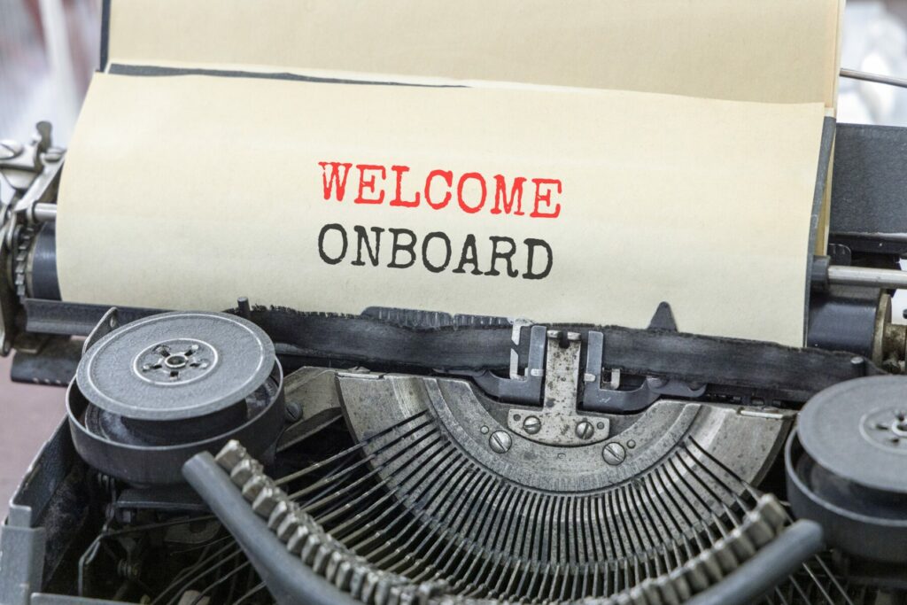 Close-up of a vintage typewriter with paper reading “WELCOME ONBOARD” fed into the roller.