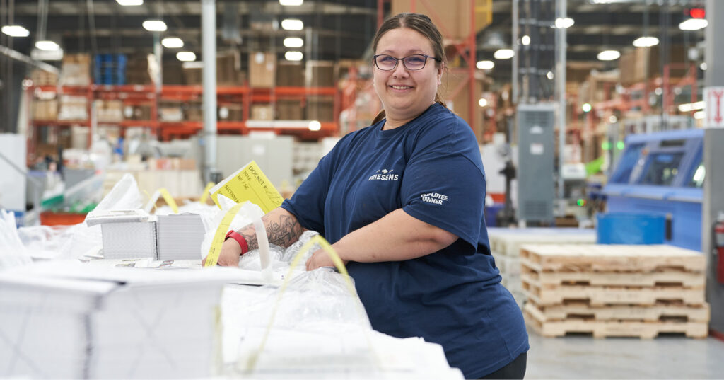 Employee-owner organizing book signatures on the production floor.