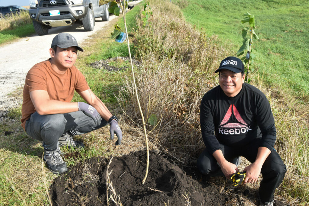Two Friesens employee-owners planting a young tree along the Trans Canada Trail