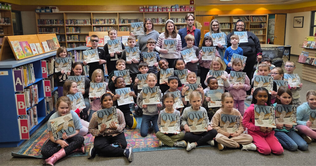 Group of Grade 2 students in a school library holding copies of Owl during an I Love to Read Month celebration.
