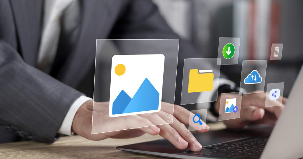 Hands typing on a laptop with floating icons for images, folders, downloads, and cloud storage.