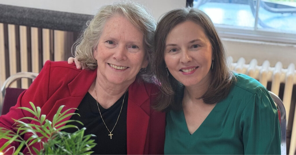 Two people seated together indoors, smiling with arms around each other during the Owl book launch party.