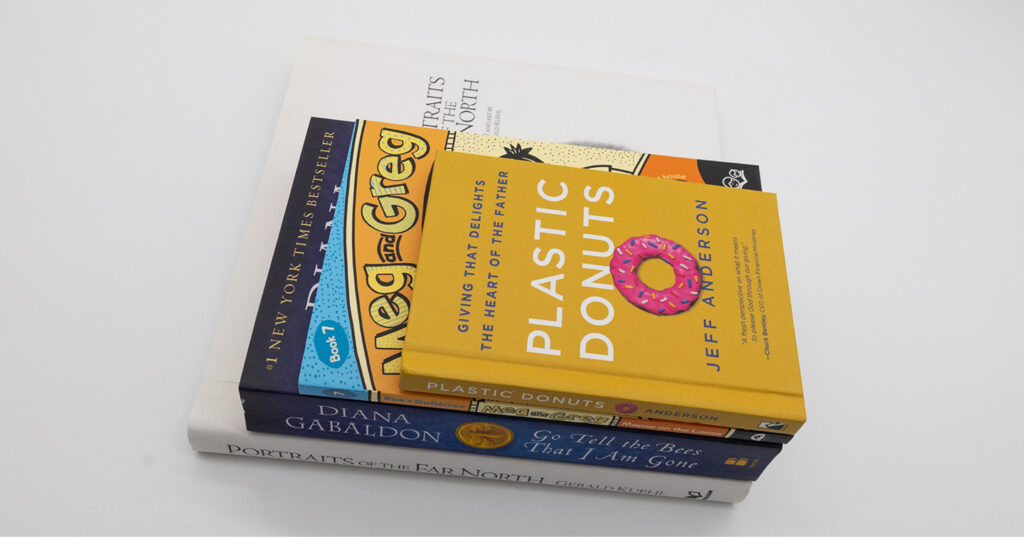 Angled stack of printed books in varying trim sizes, highlighting different book formats and dimensions on a white background