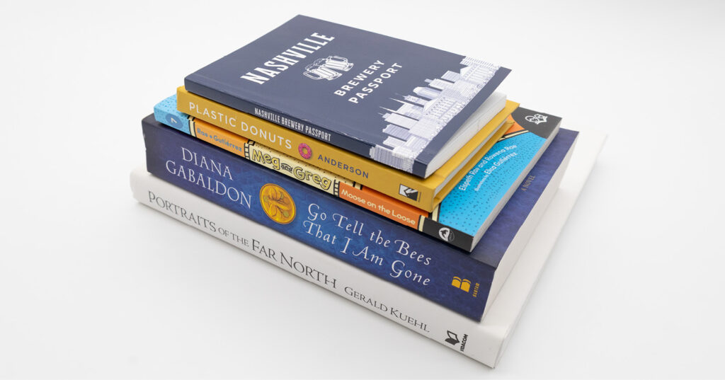 Stack of printed books in different trim sizes, showing a range of book formats and dimensions on a white background