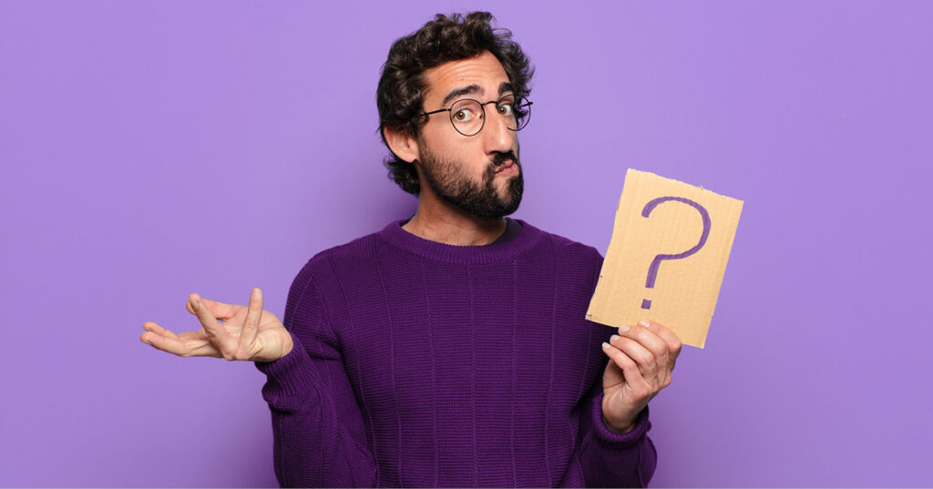 Person in a purple sweater holding a cardboard sign with a question mark against a purple background.