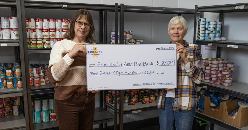 Friesens team presents a donation cheque to Rhineland & Area Food Bank inside a food pantry.