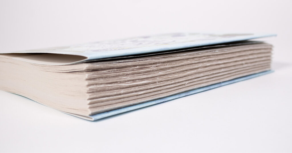 Close-up of a hardcover book showing ragged foreedges and layered paper texture along the page block.