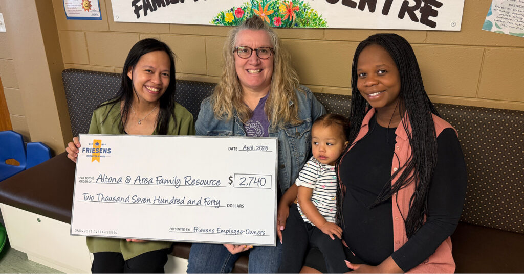 Three adults and a child seated indoors holding a cheque for $2,740 presented to Altona & Area Family Resource.