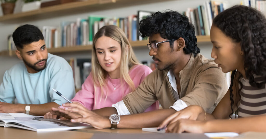 Students work together at a table, reviewing materials and sharing ideas during a collaborative planning session. Students