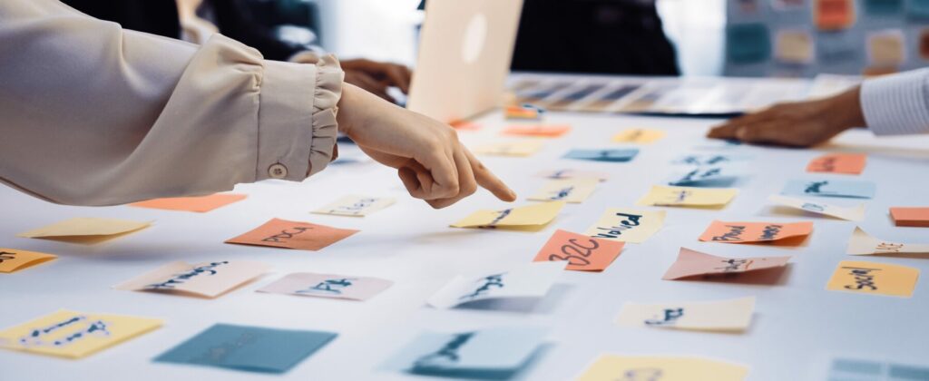 Team members collaborate around a table covered with colorful sticky notes, organizing ideas during a planning session.