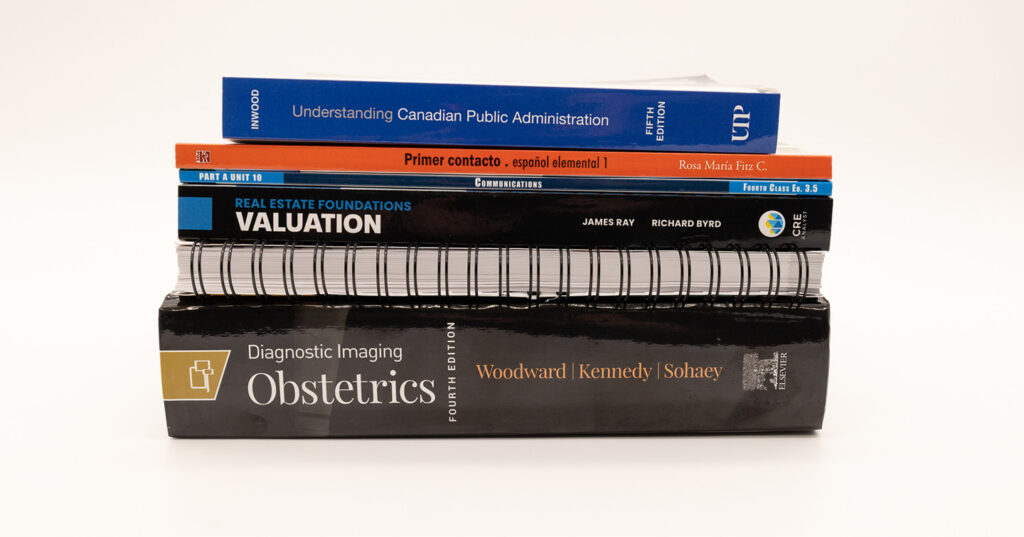 Stack of textbooks showcasing a variety of binding styles, including hardcover, softcover, and spiral-bound books.