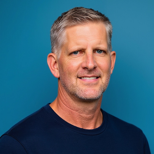 Professional headshot of a person in a navy shirt against a blue background.