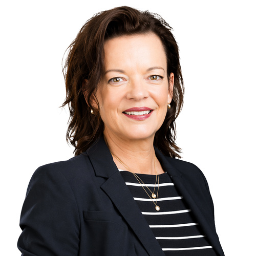 Professional headshot of a person wearing a dark blazer and striped top against a light background.