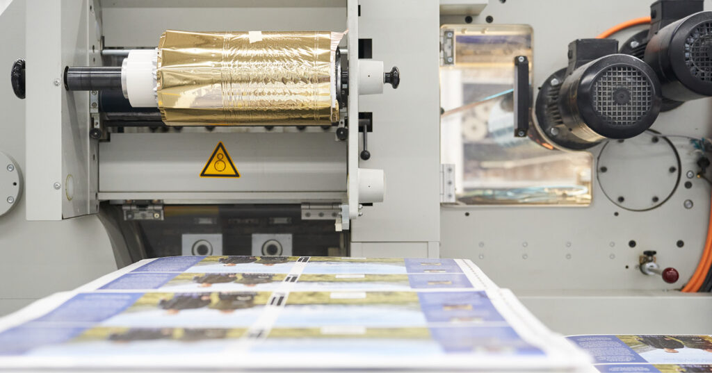Gold foil roll mounted on a book finishing machine as printed sheets move through the production process.